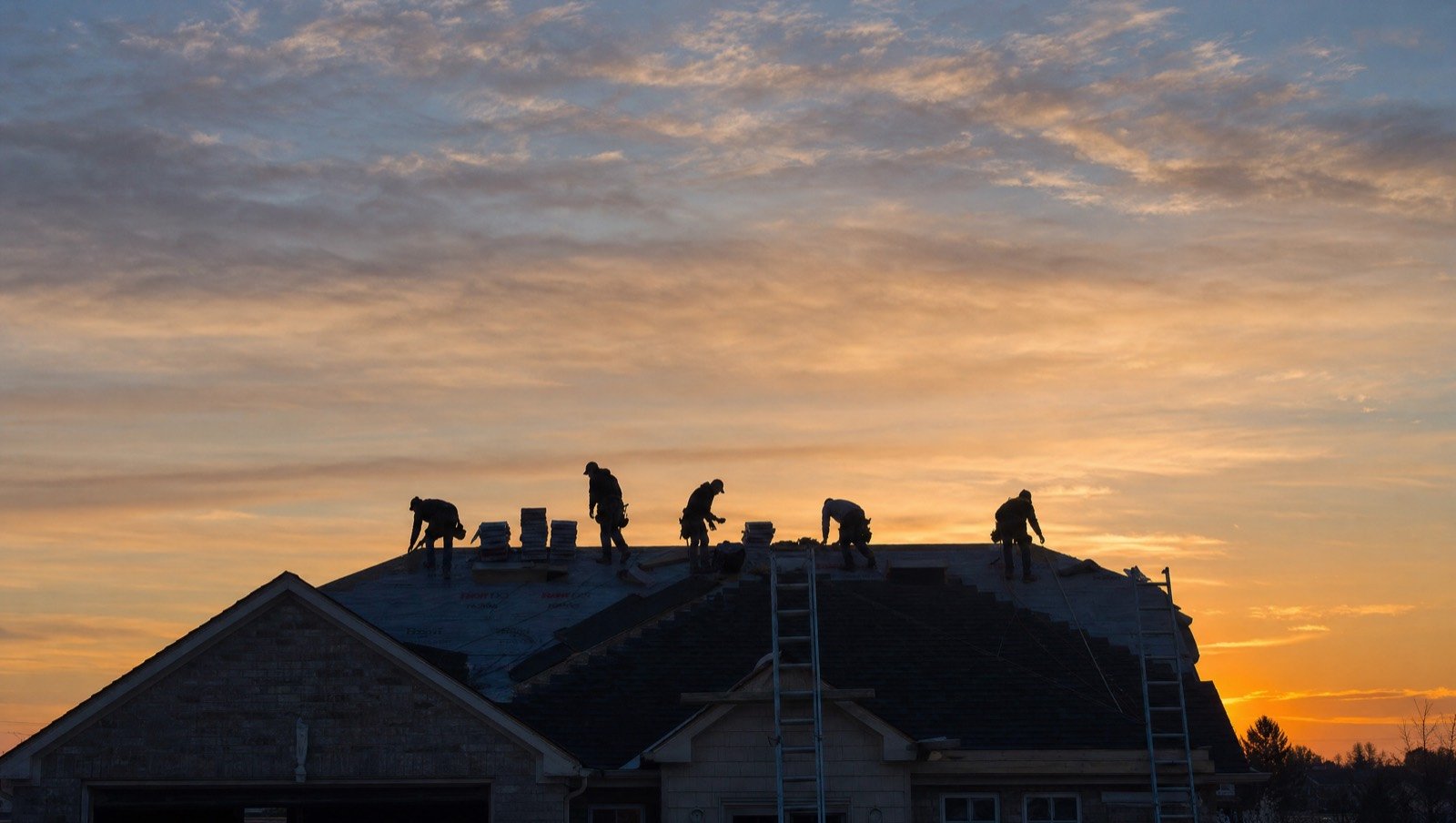 Roofing crew on a ridge line at dawn